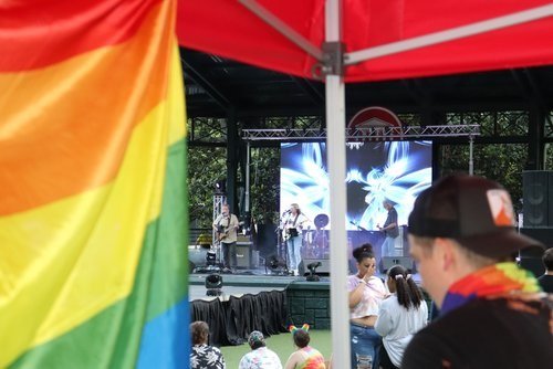 A view from a tent with a rainbow flag of the Grove stage where a band is playing