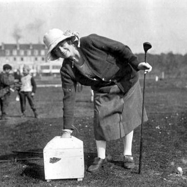 A golfer in 1921 reaches into a "tee box" to retrieve a handful of wet sand, which would then be shaped into a tee for the golf ball.